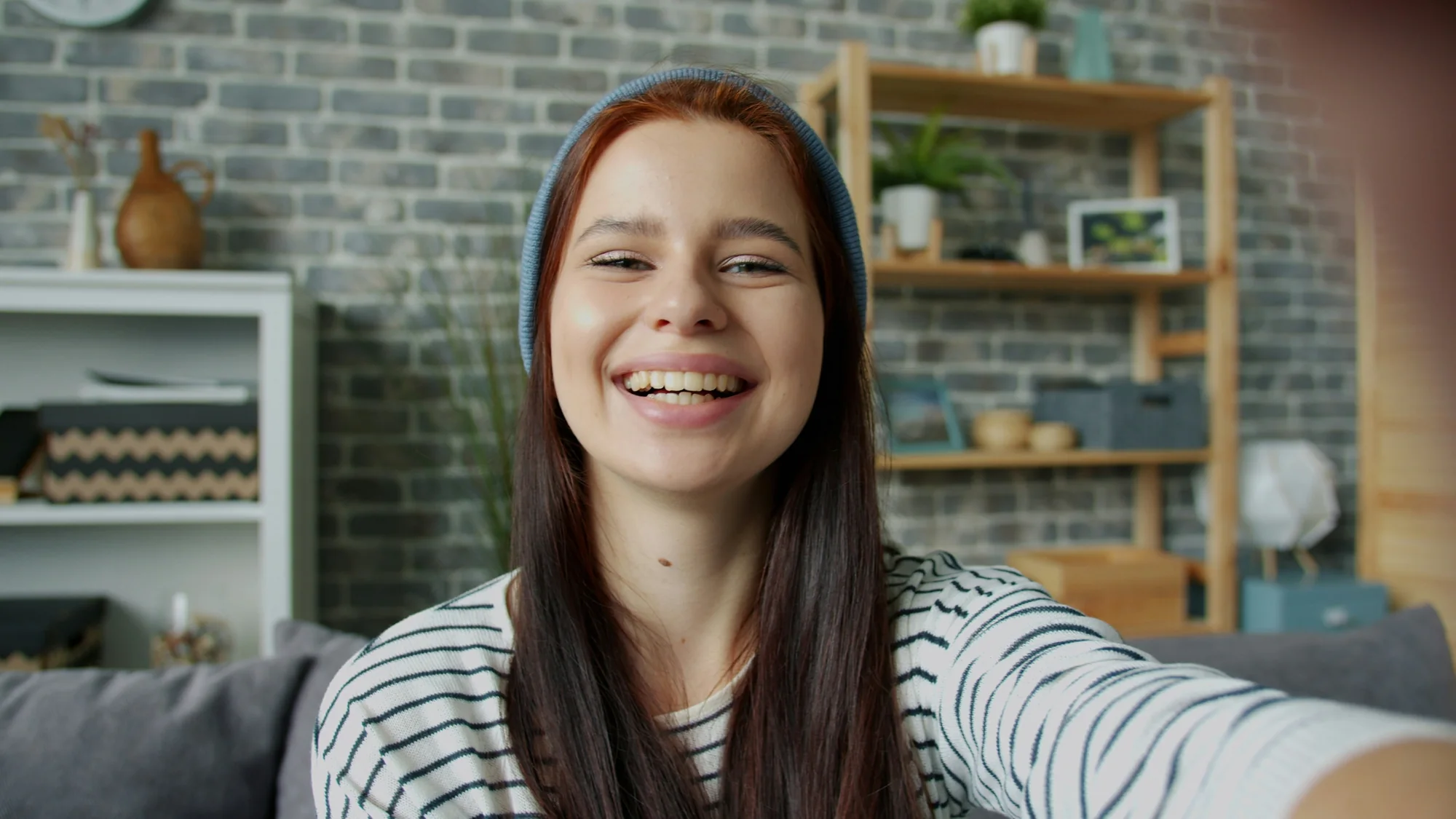 Young woman smiling at the camera wearing headphones.